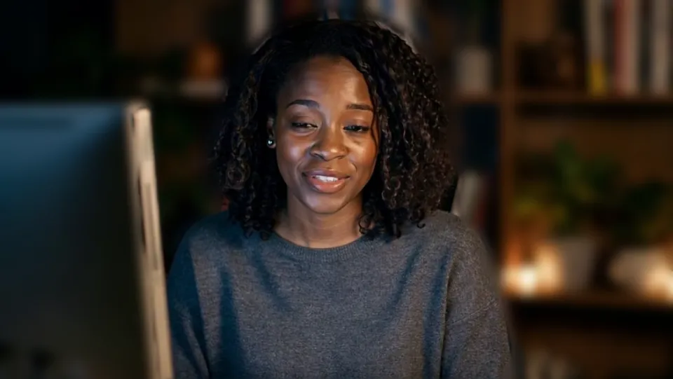Our test clip with no effect: a woman at her desk at night, bookshelves and lamps sharp behind her